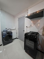 Cocina compacta con lavadora, estufa y una pequeña encimera.