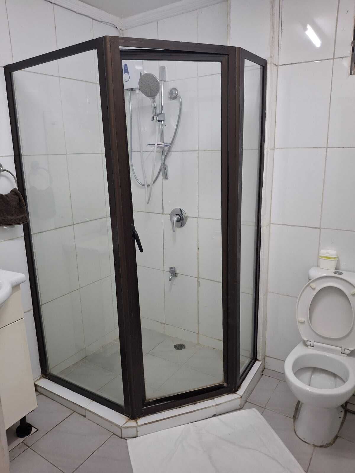 A corner shower with a glass door, a toilet, and a sink in a bathroom.