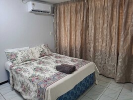 A single bed with floral bedding, a brown towel, and a blue skirted bed base.