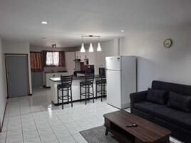 Un apartamento moderno con cocina, comedor y sala de estar. Cuenta con un refrigerador, cafetera y sofá.