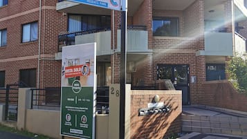 A residential building with a sign indicating 'Kitchener Av' and 'Mimulus La' at the entrance.