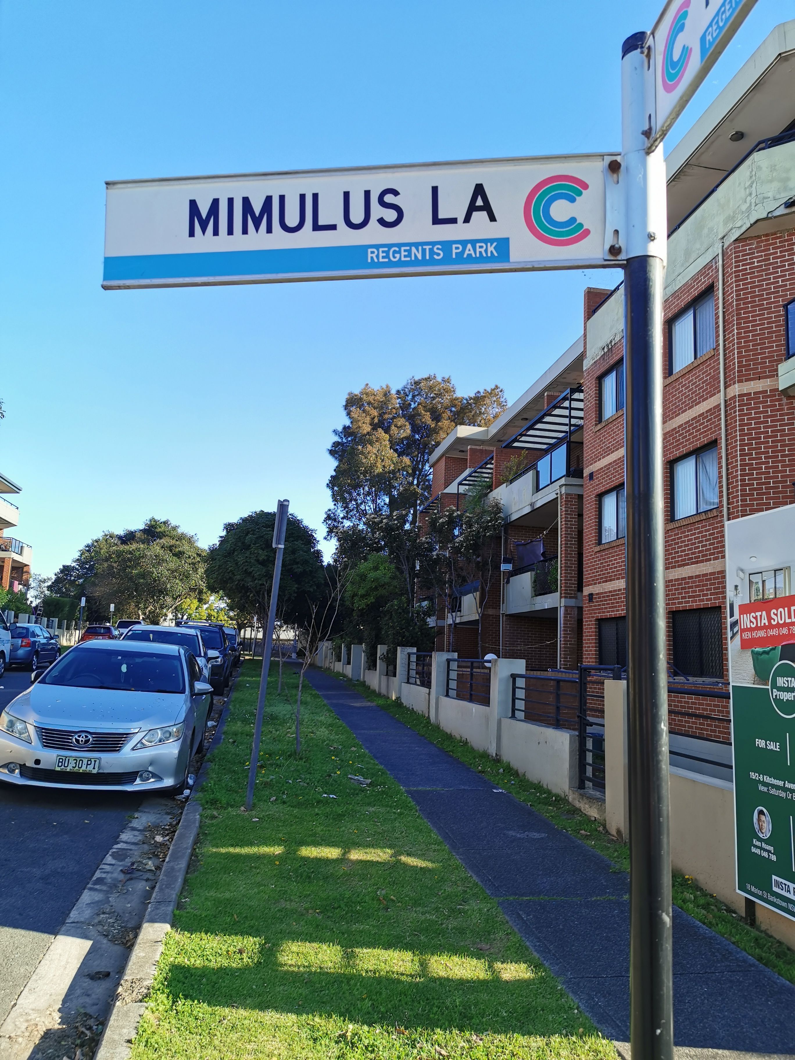 A street sign for 'MIMULUS LA' with a 'C' logo, indicating a commercial area.