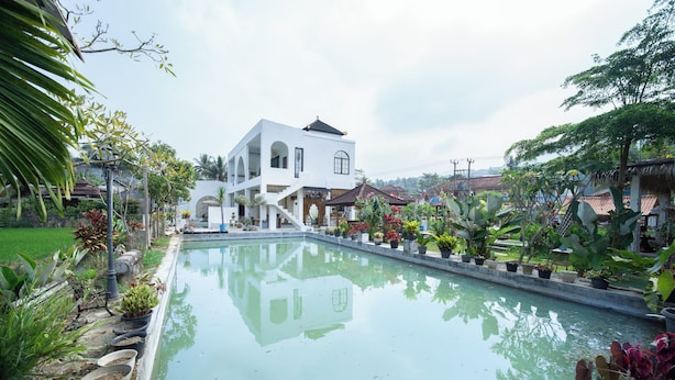 A modern white building with a pool, surrounded by tropical plants and a clear sky. - Rehat at D'Sawah Villas (Rancakalong)