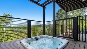 A hot tub on a wooden deck with a view of a forested landscape. - Luxe Cabin with Heated Indoor Pool, Hot Tub, Arcade & Theater near Dollywood (Sevierville)