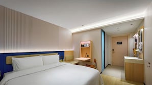 Una habitación de hotel con cama, mesita de noche y baño pequeño con lavabo y espejo.