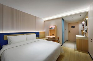 Una habitación de hotel con cama, mesita de noche y baño pequeño con lavabo y espejo.