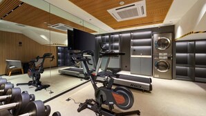 Un gimnasio con equipo de cardio, pesas y una lavadora.
