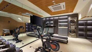 Un gimnasio con equipo de cardio, pesas y una lavadora.