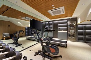 Un gimnasio con equipo de cardio, pesas y una lavadora.