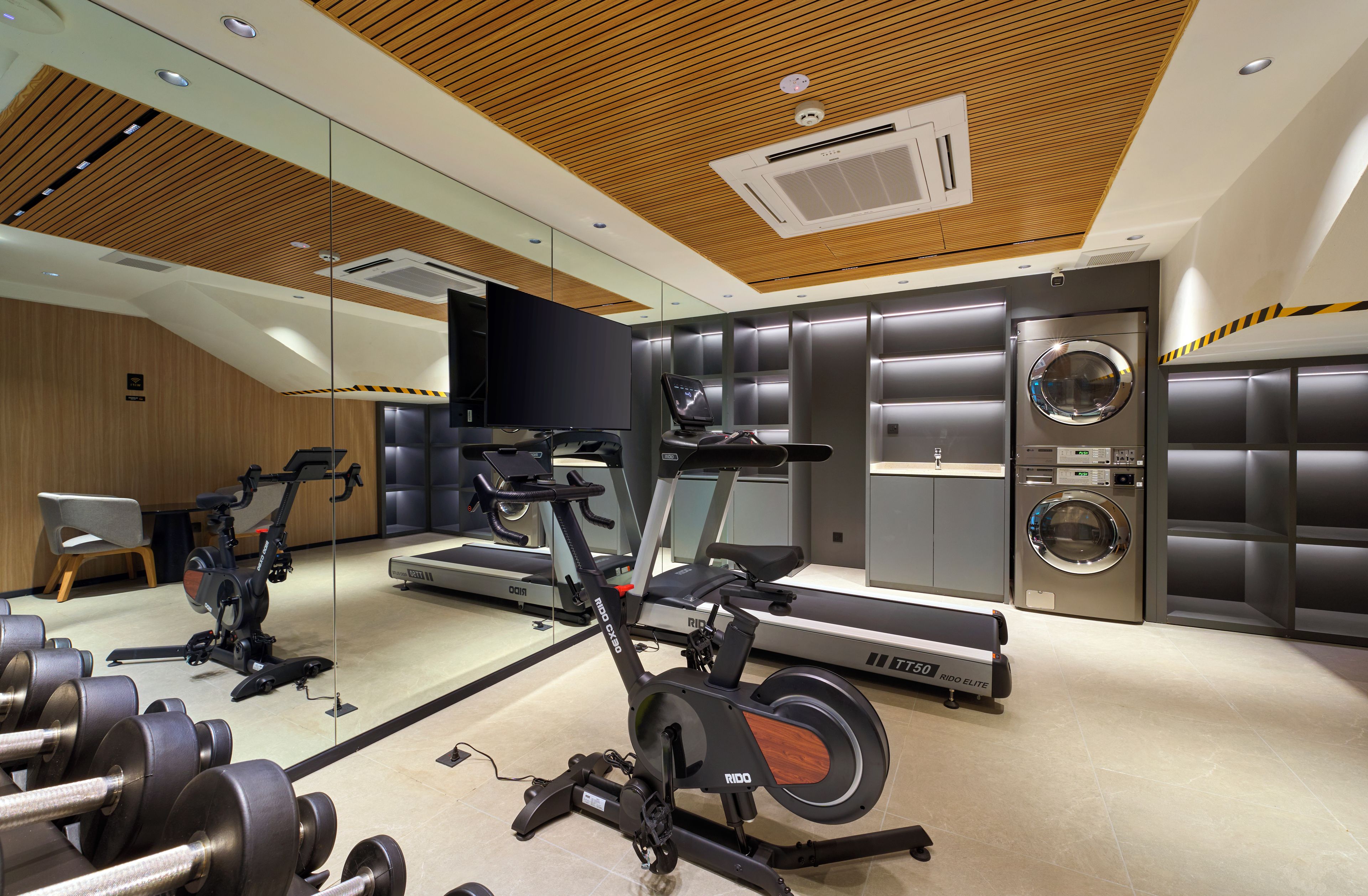 Ein modernes Fitnessstudio mit Cardiogeräten, Krafttrainingsmaschinen und einem großen Spiegel.