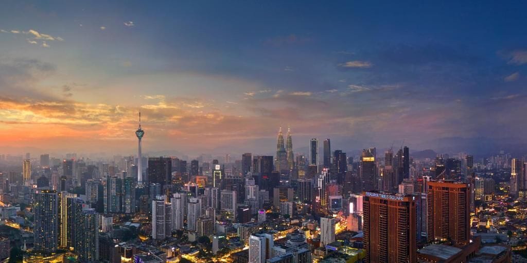 A cityscape at dusk with high-rise buildings and a prominent tower.