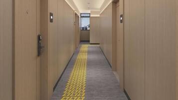 Un pasillo de hotel con puertas de madera, alfombra estampada y piso de color claro.