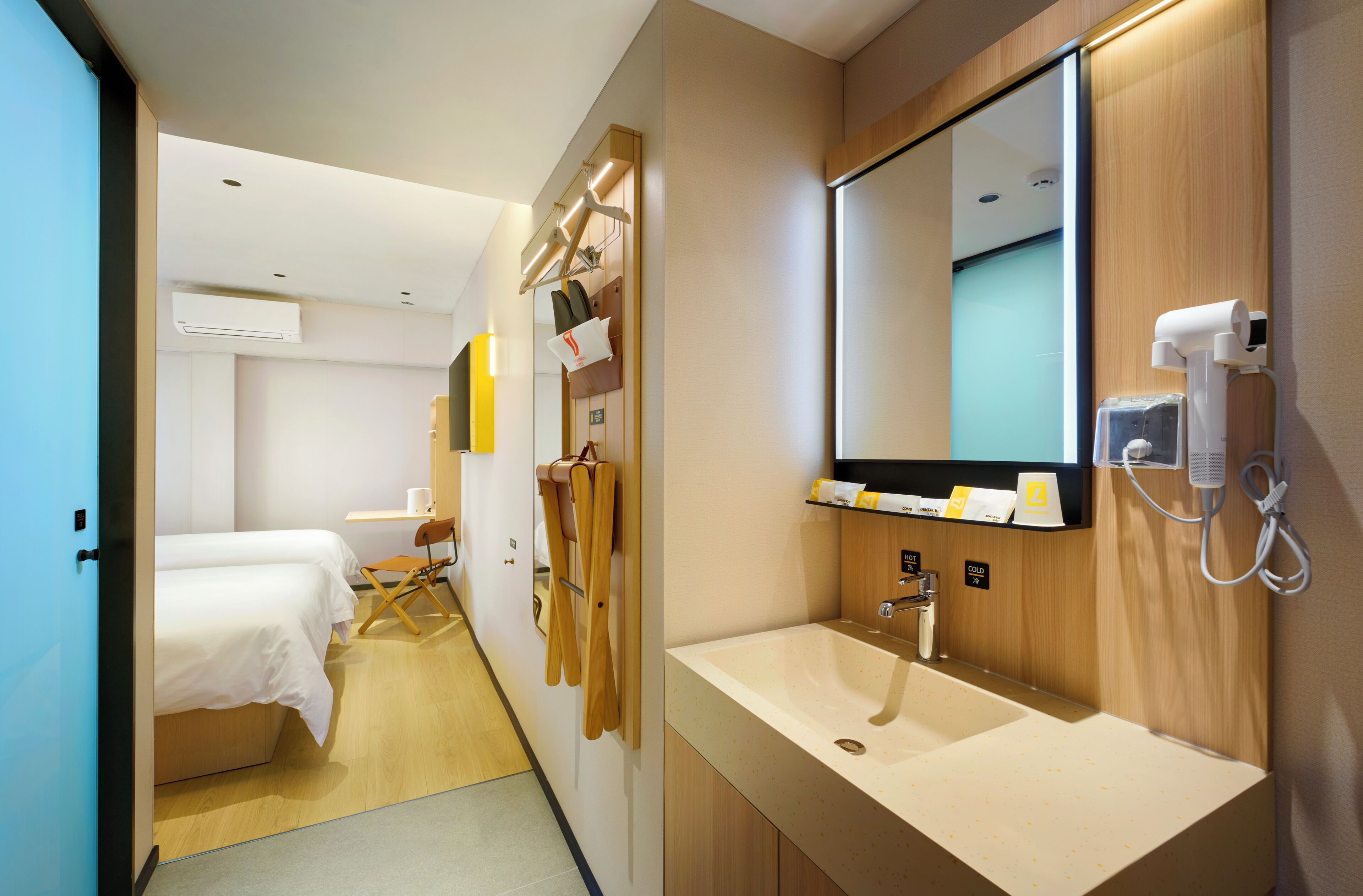Ein Hotelzimmer mit Bett, Schreibtisch, Spiegel, Waschbecken und Duschbereich.
