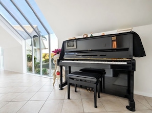 A Yamaha grand piano in a spacious room with a large window.