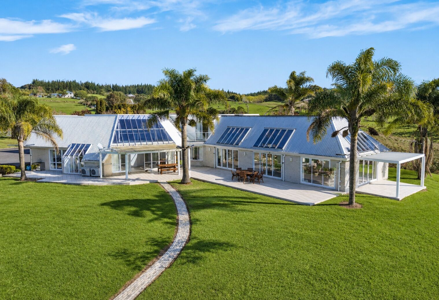 A modern house with solar panels, a patio, and a view of the countryside.