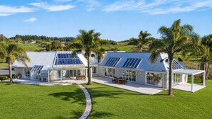 Uma casa moderna com painéis solares, um pátio e vista para o campo.