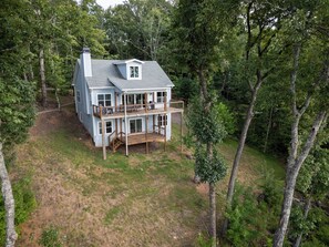 A two-story house with a balcony and a deck, surrounded by trees. - Mountain Views Retreat | Retreat for 2 | Breathtaking Scenery | Firepit (Clarkesville)