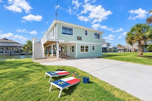 A two-story house with a balcony, a number '23002' on the front, and a flag on the lawn. - Waterfront 3BR | Boat Slip Access & Deck | Sleeps 10 (Galveston)