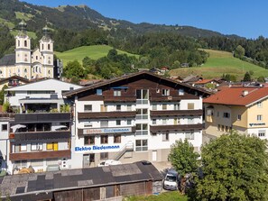 A multi-story building with a sign for 'Electro Biedermann' and a church in the background. - Two penthouse apartments in the center. (Hopfgarten im Brixental)