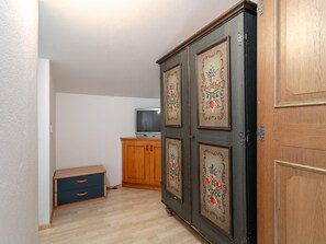 A room with a wooden wardrobe, a television on a wooden cabinet, and a small wooden cabinet with drawers. - Two penthouse apartments in the center. (Hopfgarten im Brixental)