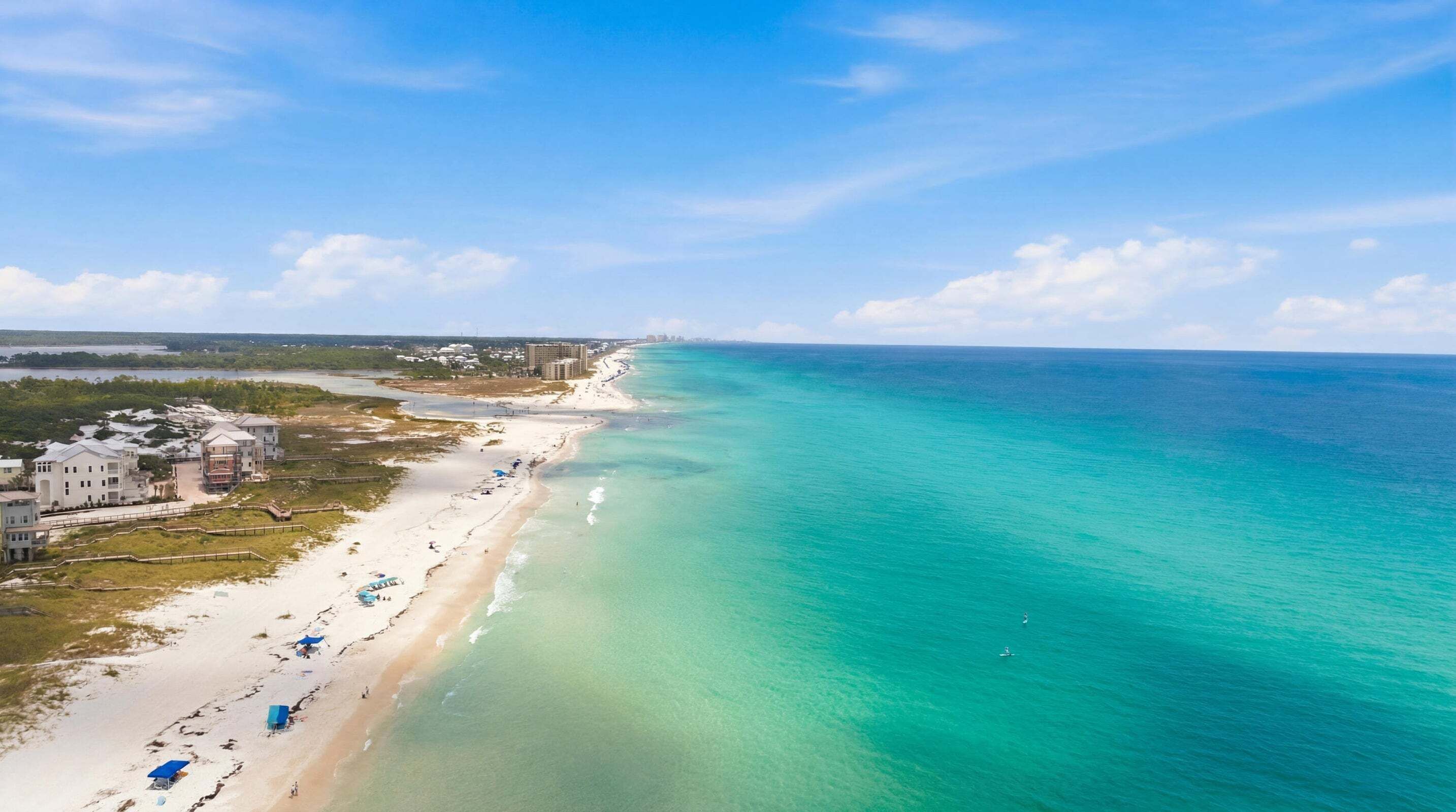 Propiedad costera con playa, vista al océano y edificios colindantes.