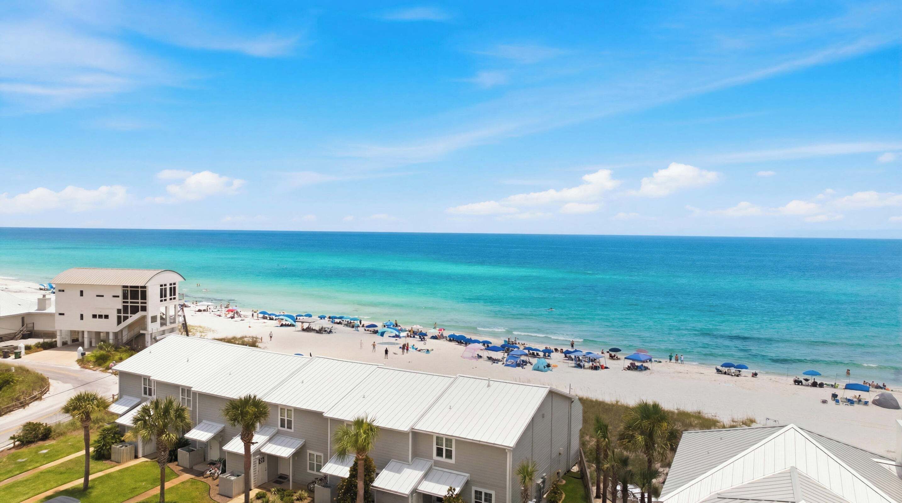 Une propriété située en bord de mer, avec une rangée de maisons de plage, une plage de sable et l’océan.
