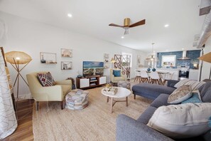 Een moderne woonkamer met een bank, fauteuil, salontafel en een televisie.
