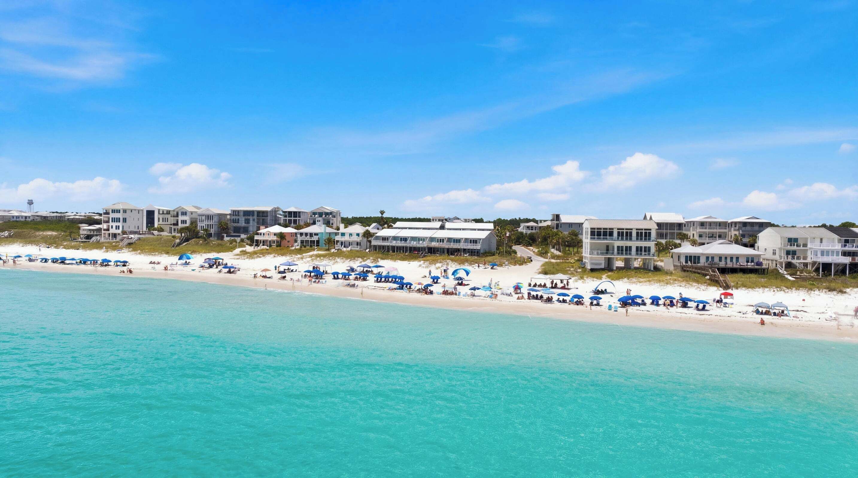 A beachfront property with multiple buildings, a sandy beach, and clear turquoise waters.