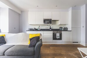 A modern kitchen with white cabinets, a microwave, a Bosch oven, and a coffee maker. - Stylish 2BR | Fast Links to Central London (Croydon)