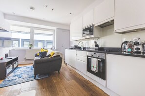 A modern kitchen with white cabinets, a black countertop, and a Bosch oven. - Stylish 2BR | Fast Links to Central London (Croydon)