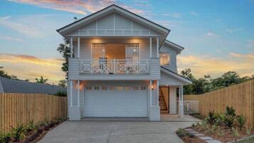 A two-story house with a balcony, a garage, and a wooden fence surrounding the property.