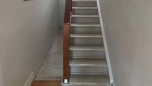 A narrow hallway with a wooden handrail and a carpeted floor leading to a staircase. - City Loft | Stylish CBD Stay + River Walks (Rockhampton)