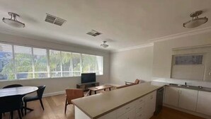 A spacious kitchen with a central island, dining area with chairs, and a large window providing natural light. - City Loft | Stylish CBD Stay + River Walks (Rockhampton)
