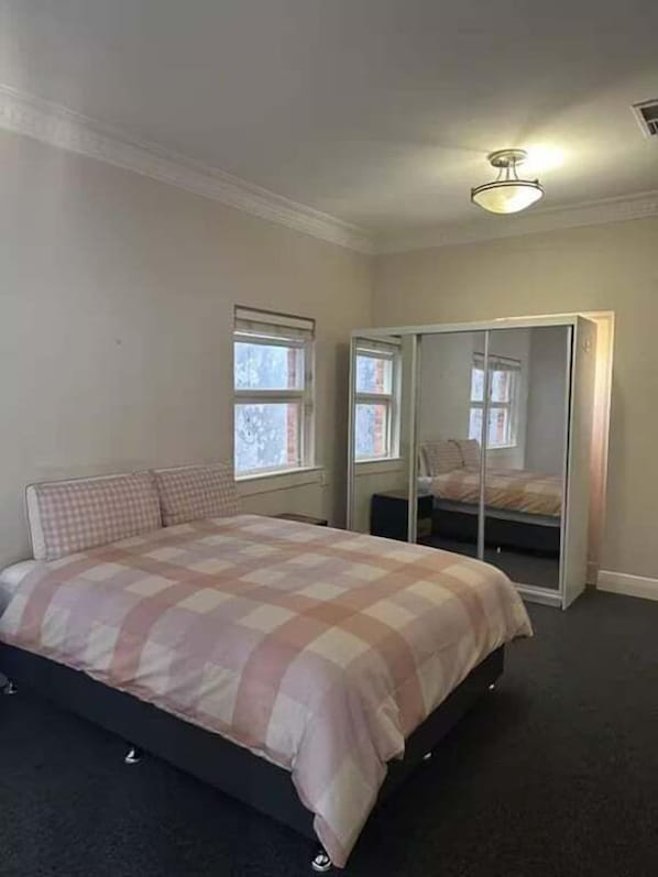 A bedroom with a bed, a wardrobe, and a window.