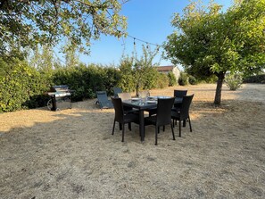 Ein Essbereich im Freien mit Grill und Stühlen.
