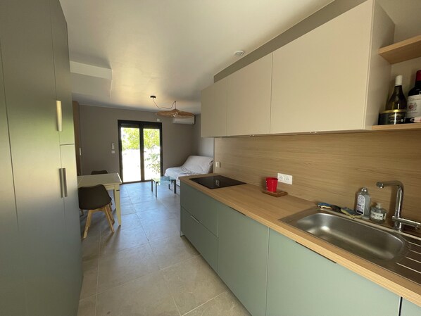 A modern kitchen with a central island, a built-in sink, and a dining area with a table and chairs. - Vrbo Property (La Plaine-sur-Mer)