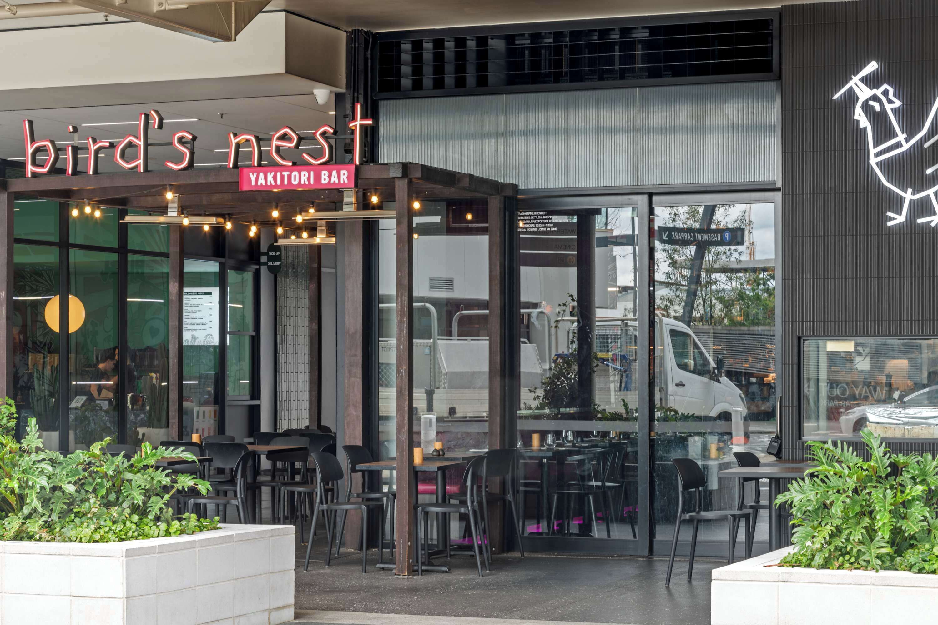 A restaurant named 'Bird's Nest' with outdoor seating and a glass door entrance.