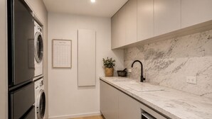 Uma cozinha moderna com eletrodomésticos embutidos, painel de fundo de mármore e um calendário semanal.