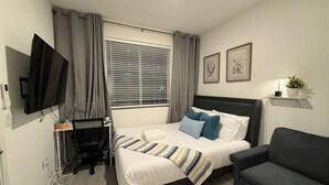 Une chambre d’hôtel comprenant un lit, un bureau, une chaise, une télévision et un canapé.