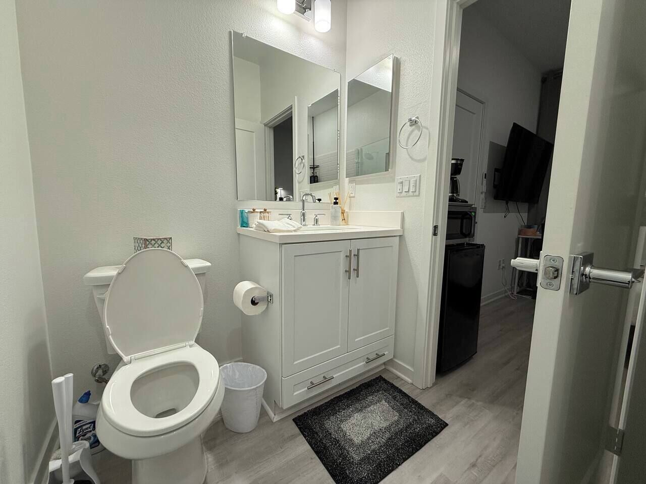 Een badkamer met toilet, wastafel, spiegel en kastjes.