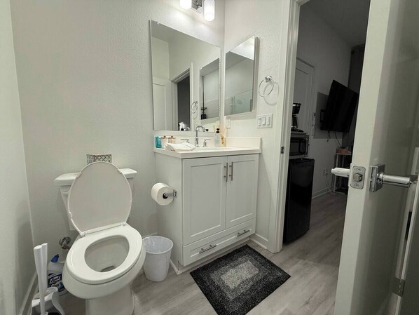 Un baño con inodoro, lavamanos, espejo y armarios.