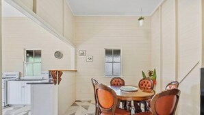 A dining area with a table and chairs, a kitchen area with appliances, and a staircase. - City Cottage (Rockhampton)