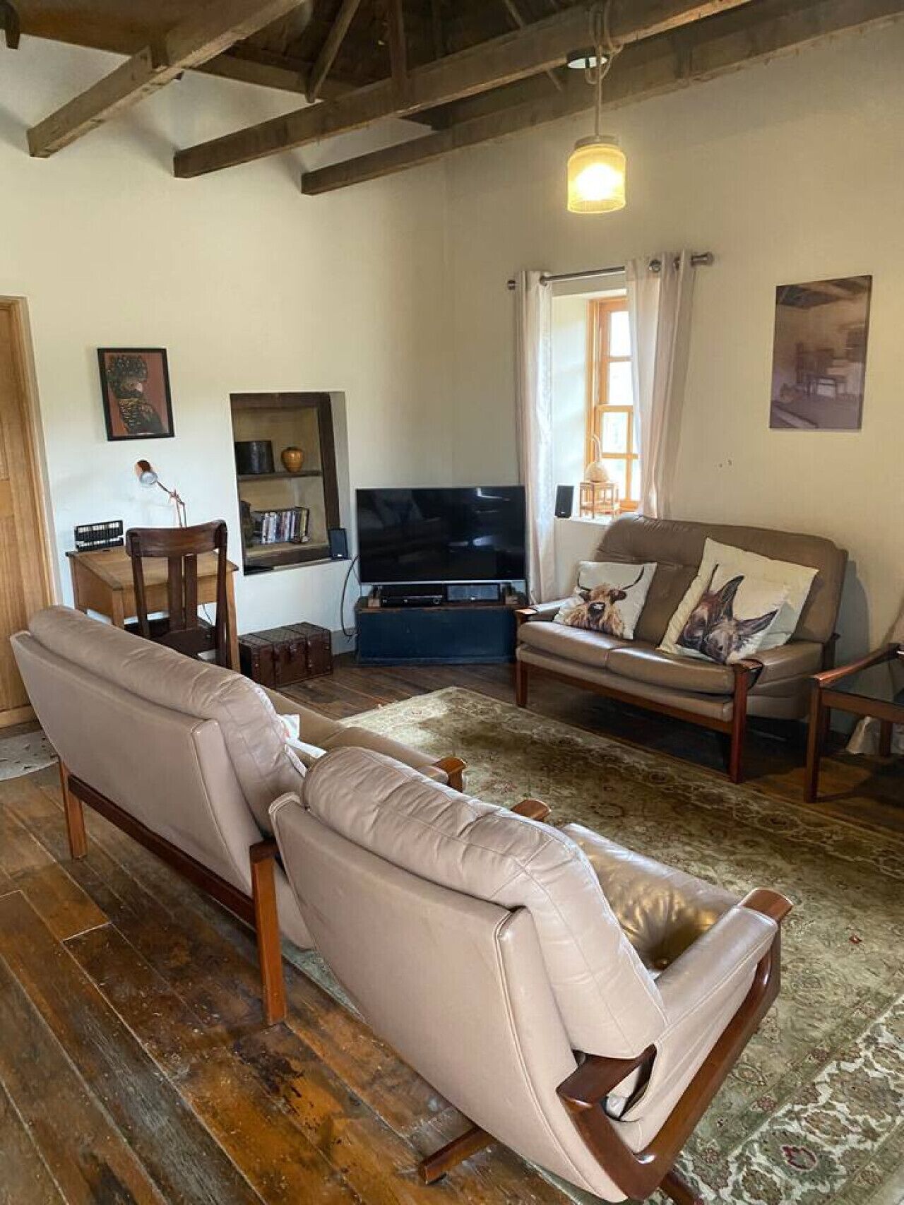 A living room with a sofa, a television, a wooden table, and a patterned rug.