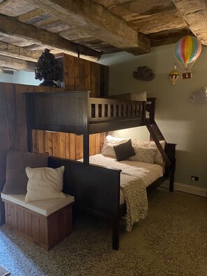 A bunk bed room with a wooden ceiling, a small seating area, and a hot air balloon decoration.