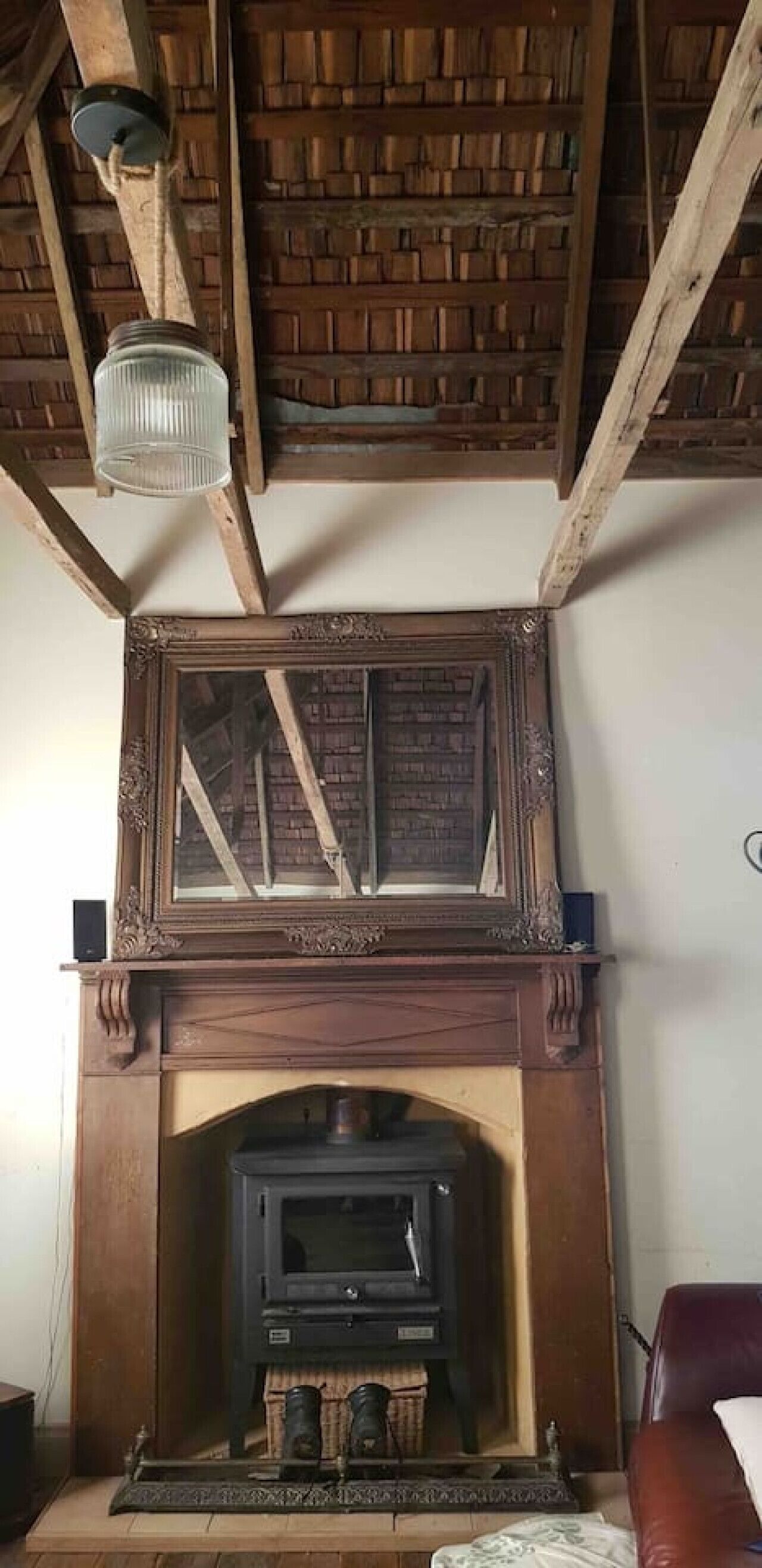 A fireplace with a mirror above it, a wooden mantel, and a modern stove below.