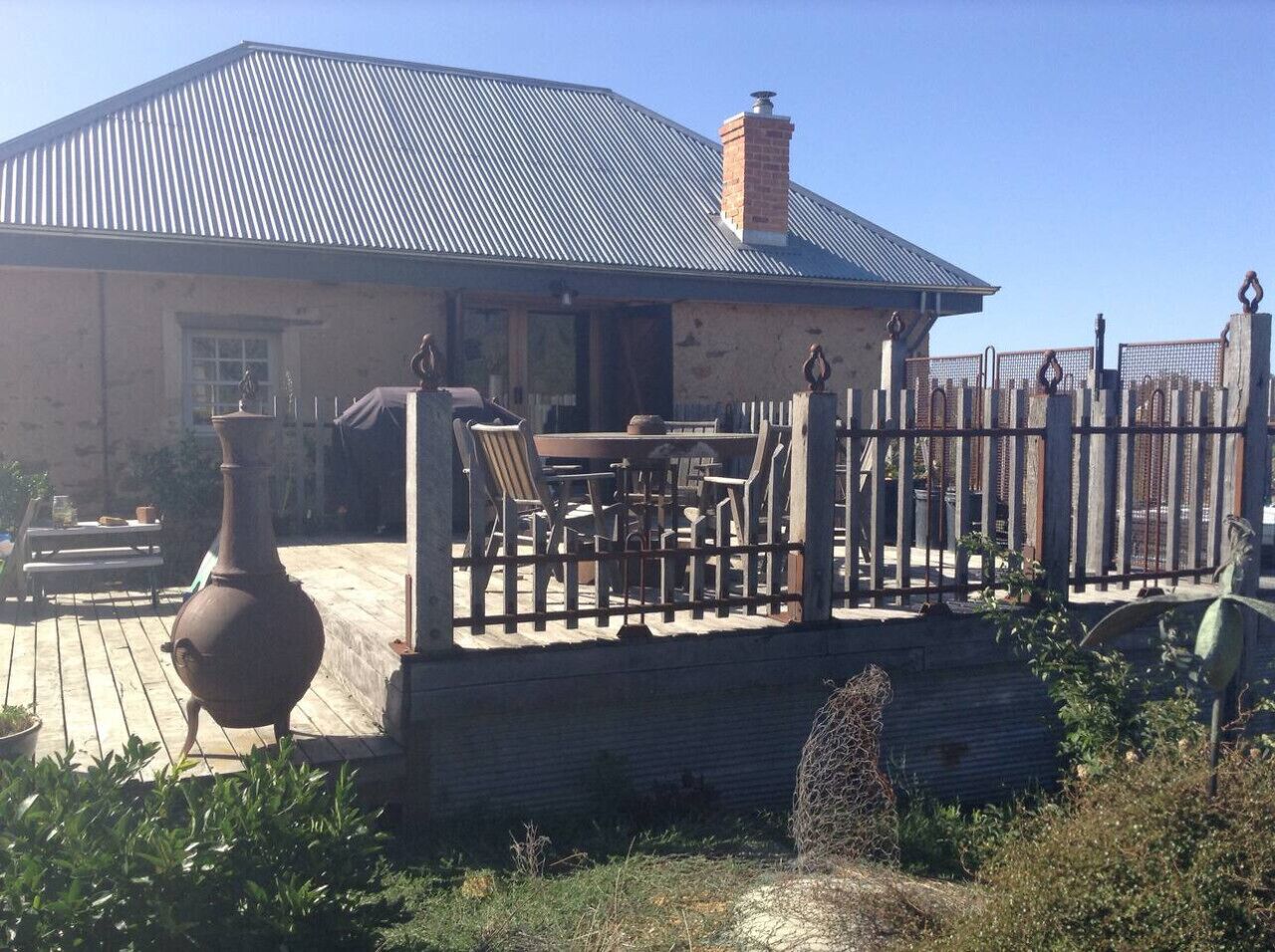 A house with a metal roof, a wooden deck, and a fenced patio area.