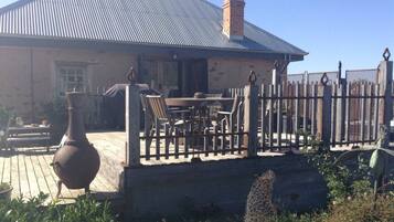 A house with a metal roof, a wooden deck, and a fenced patio area.