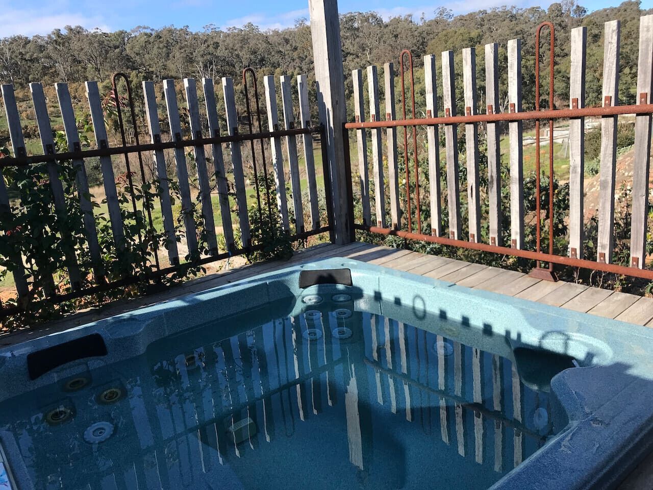 A hot tub with a wooden fence and a wooden deck in the background.