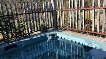 A hot tub with a wooden fence and a wooden deck in the background.