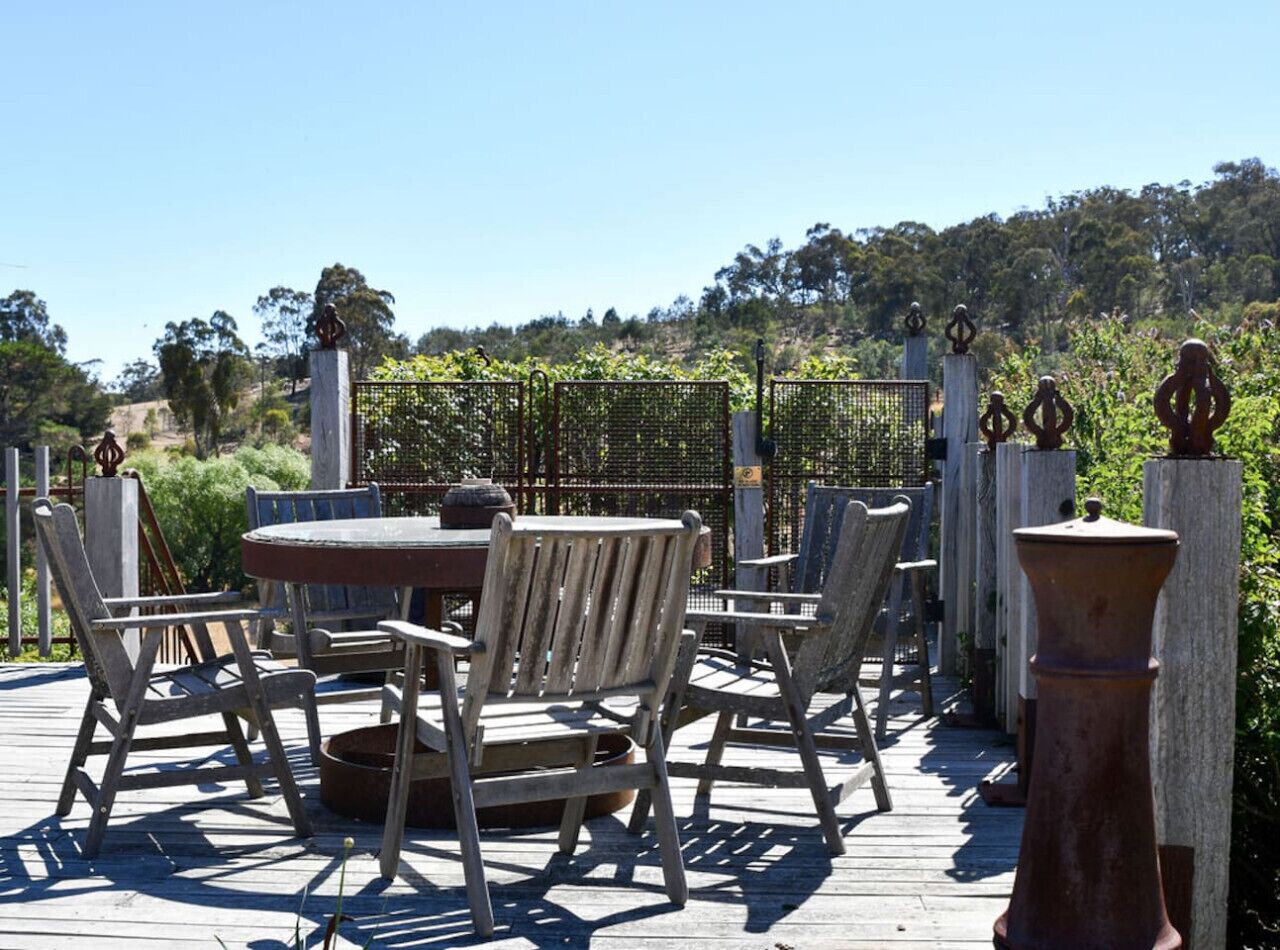 An outdoor patio with a round table and chairs, surrounded by a wooden fence and decorative pillars.